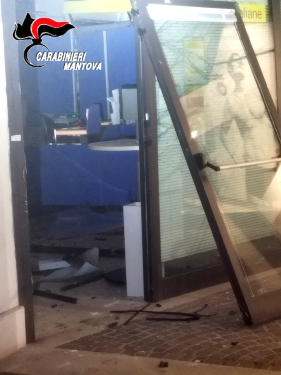 La porta scardinata dallo scoppio provocato dai banditi