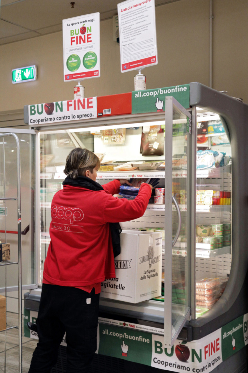 Un'operatrice Coop mentre riordina i prodotti coinvolti nel progetto "Buon fine"